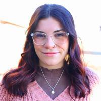 Smiling woman in a pink sweater and clear glasses