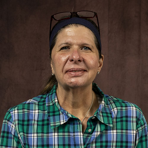 Woman with dark hair and glasses on head