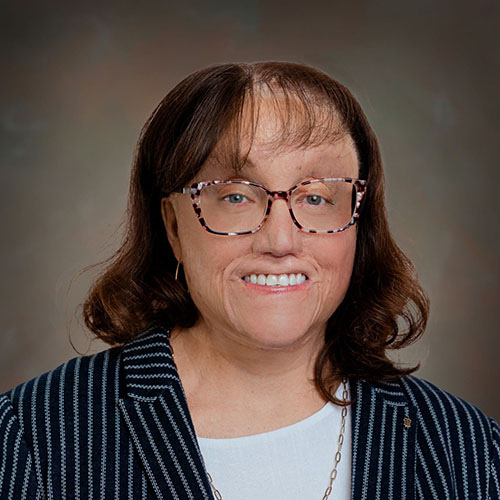 Woman with long dark hair and glasses