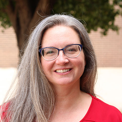 woman with long gray hair and glasses