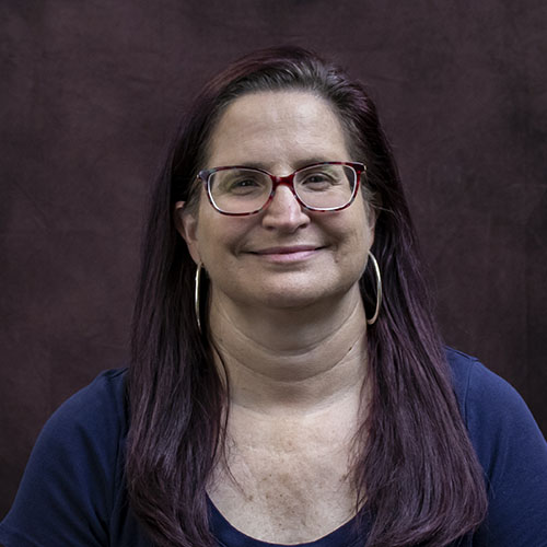 Woman with long dark hair and glasses