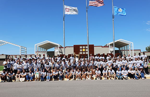 Students pose in front of campus for an orientation picture